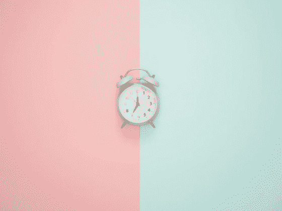 Green alarm clock with a pink and teal background