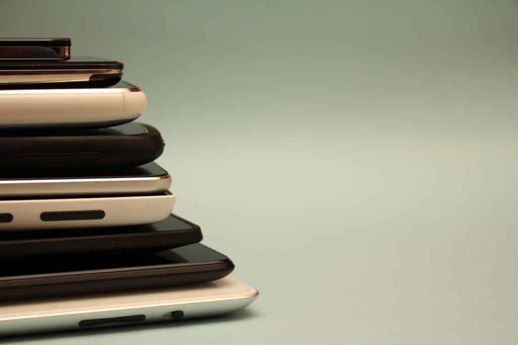 A pile of different hand-held devices are stacked on top of one another