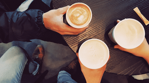 Three employees hold lattes to talk during a coffee break
