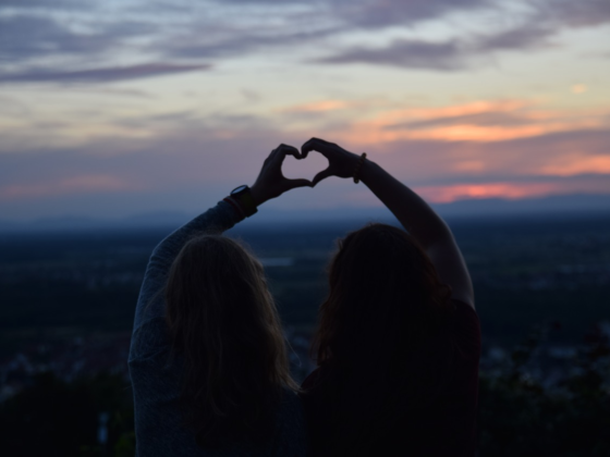 two friends making a heart shape with their hands